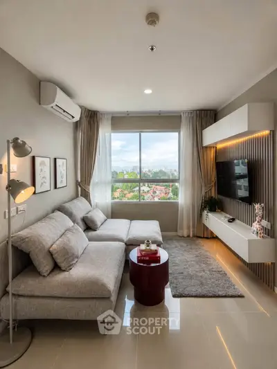 Modern living room with large window offering city view, stylish gray sofa, and wall-mounted TV unit.