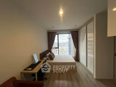 Modern bedroom with city view, featuring a sleek desk and large wardrobe, perfect for urban living.