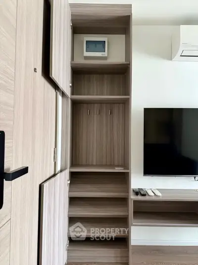 Modern apartment interior with stylish wooden storage and wall-mounted TV, showcasing efficient use of space.
