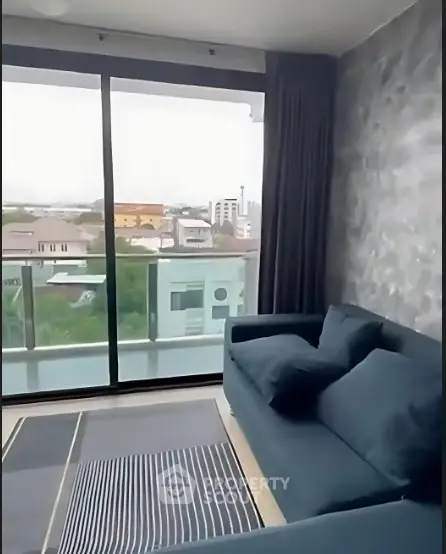 Modern living room with large windows offering a stunning city view and stylish furnishings.