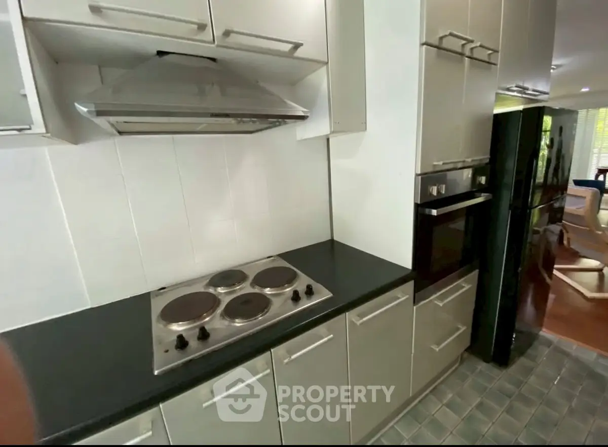 Modern kitchen with sleek cabinetry and electric stove in a stylish apartment.