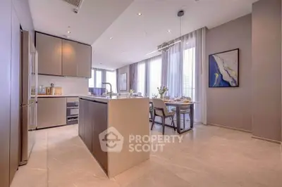 Modern kitchen with open layout and dining area, featuring sleek cabinetry and ample natural light.