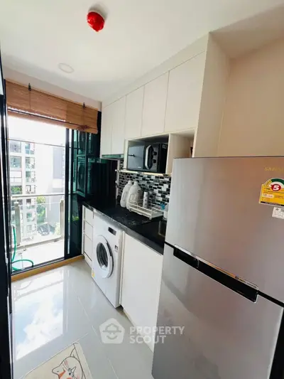 Modern kitchen with balcony view, featuring sleek appliances and stylish backsplash.