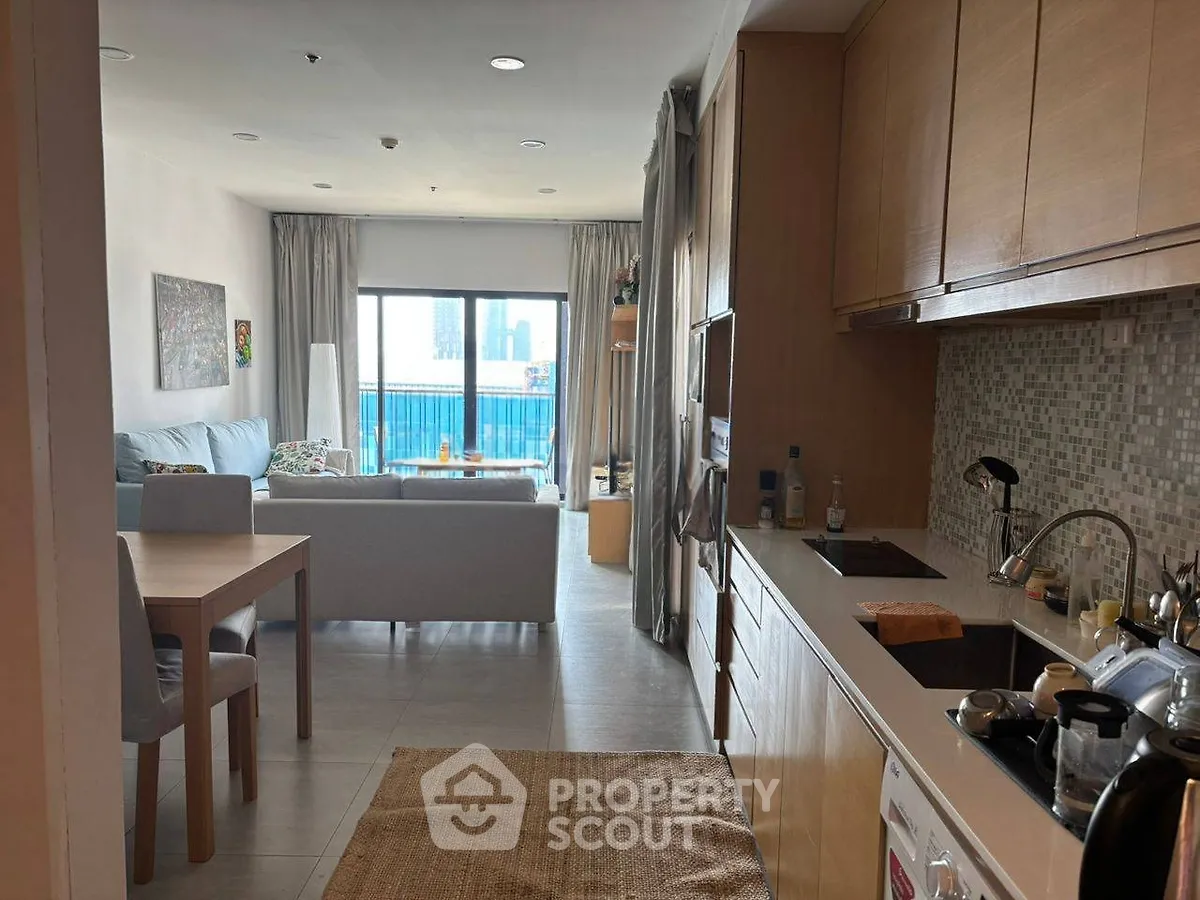 Modern open-layout living room and kitchen with city view balcony, ideal for urban living.