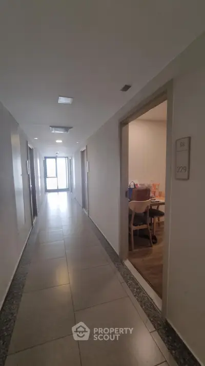 Modern apartment hallway with open door revealing cozy interior space.