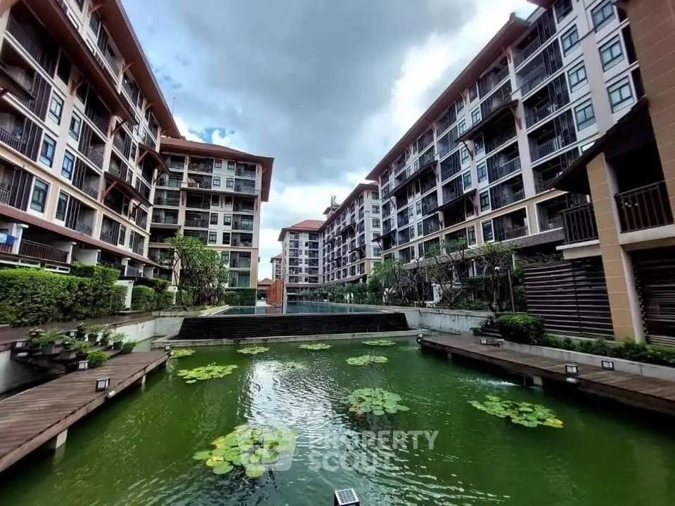 Modern apartment complex with serene pond and lush greenery