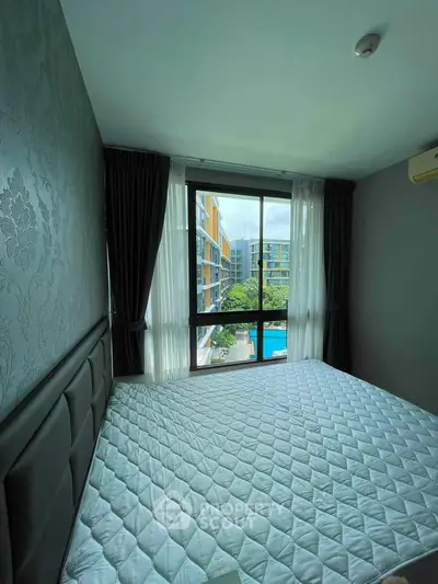 Cozy bedroom with large window offering a pool view in modern apartment.