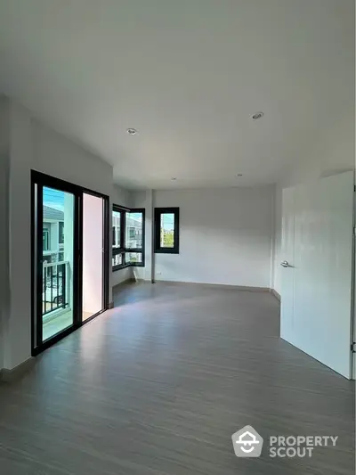 Spacious empty room with large windows and balcony access