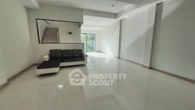 Spacious living room with gleaming tiled floors, modern staircase, and abundant natural light, perfect for elegant entertaining and comfortable living.
