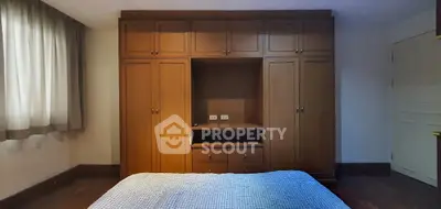 Spacious bedroom with built-in wooden wardrobe and cozy bed