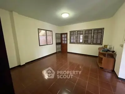 Spacious empty room with tiled floor and wooden windows in a residential property.