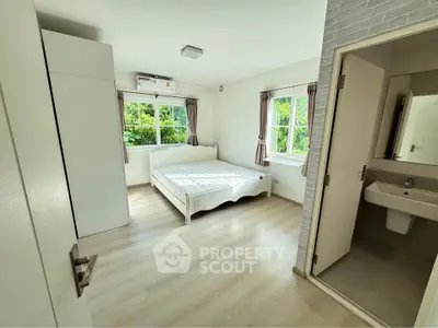 Bright bedroom with large windows and ensuite bathroom in modern home