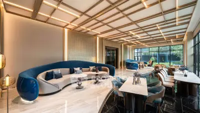 Luxurious modern living room with elegant furniture and large windows offering garden views.