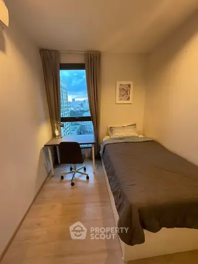 Cozy bedroom with city view, featuring a single bed and study desk.