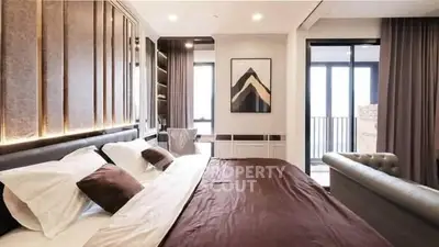 Luxurious bedroom with elegant decor and balcony access in modern apartment.