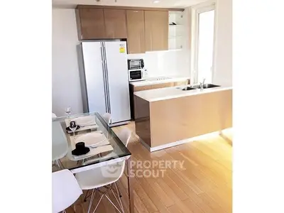 Modern kitchen with sleek cabinetry and dining area in open layout apartment.