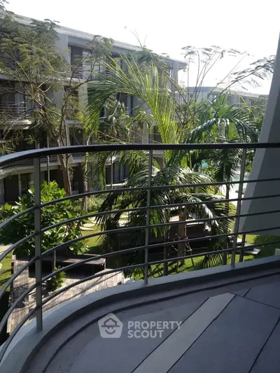 Luxurious balcony view overlooking lush garden and modern architecture in a serene residential complex.