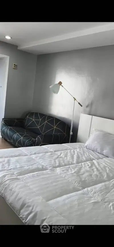 Modern bedroom with stylish sofa and cozy bed in a well-lit space.