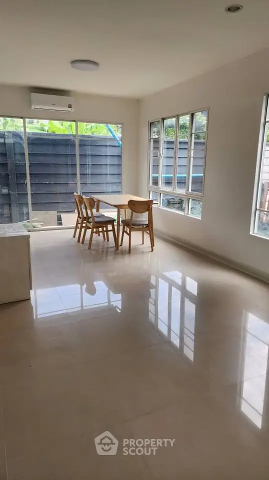 Bright dining area with large windows and modern furniture in a spacious room.