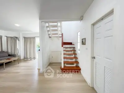 Spacious modern living room with wooden staircase and natural light