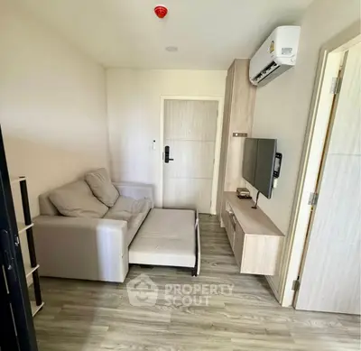 Cozy living room with modern sofa and wall-mounted TV in a compact apartment.