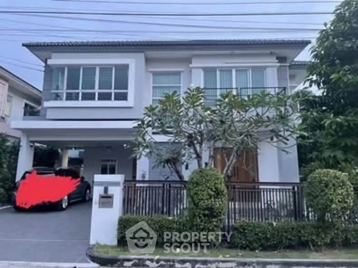 Modern two-story house with driveway and lush greenery in a serene neighborhood.