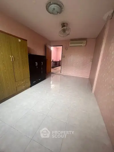 Spacious bedroom with pink walls, air conditioning, and ample storage space.