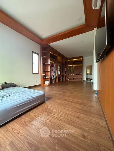 Spacious bedroom with wooden flooring and walk-in closet