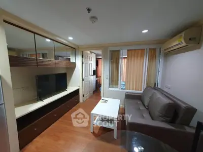 Modern living room with sleek furniture and large TV in a cozy apartment setting.