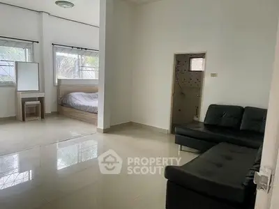 Spacious living area with modern sofa and cozy bedroom nook, perfect for urban living.