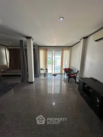 Spacious living room with glossy floors and large windows leading to a balcony, perfect for natural light.