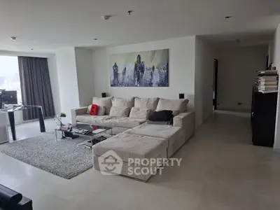 Spacious modern living room with large sofa and city view, perfect for relaxation.