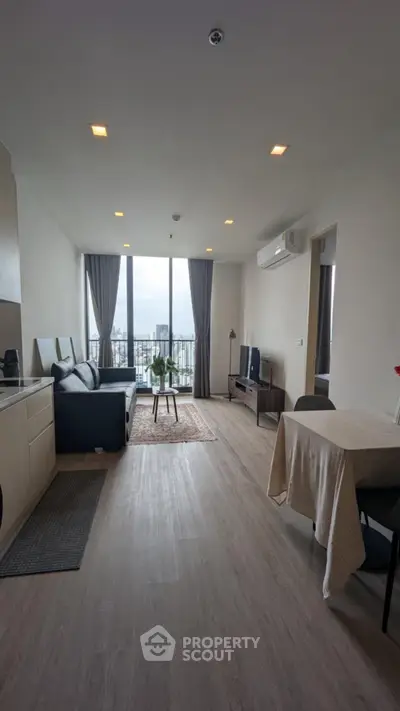 Modern living room with city view, stylish decor, and open layout in a high-rise apartment.