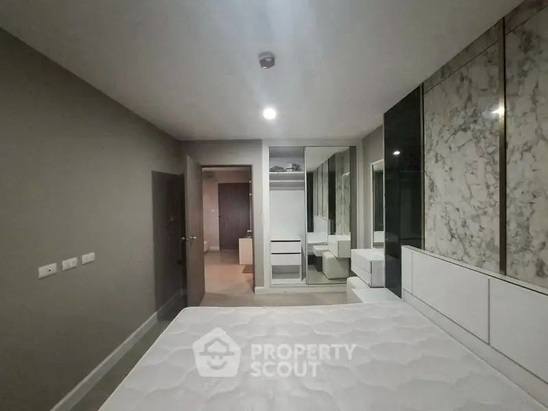 Modern bedroom with stylish marble accent wall and built-in storage solutions.