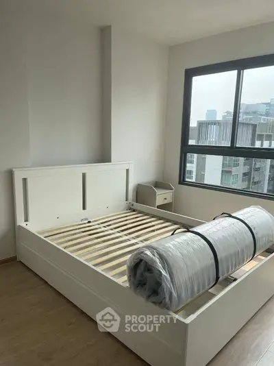 Modern bedroom with large window and new bed frame in urban apartment