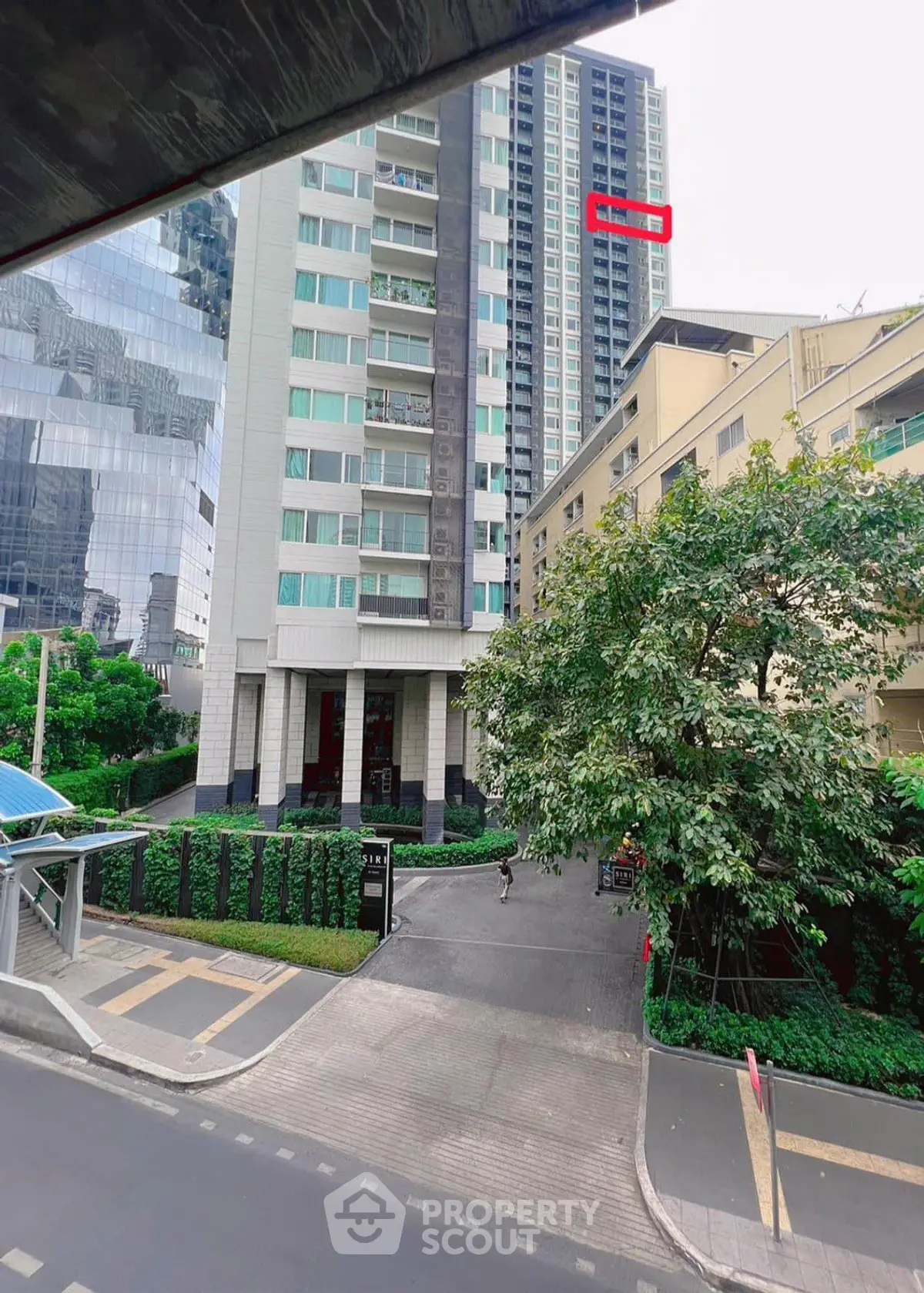 Modern high-rise building with lush greenery and urban surroundings