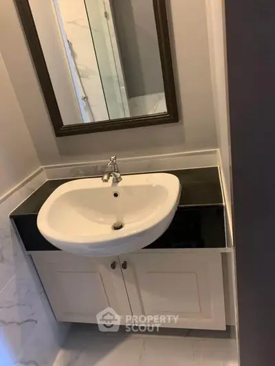Modern bathroom with sleek sink and elegant mirror in a stylish real estate property.
