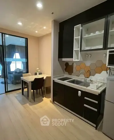 Modern kitchen with sleek black cabinets and dining area in open layout apartment.