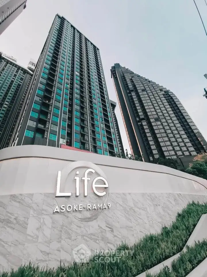Modern high-rise condominium Life Asoke-Rama 9 with sleek architecture and lush greenery.