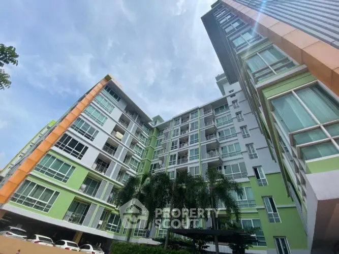 Modern multi-story residential building with vibrant green accents and palm trees.