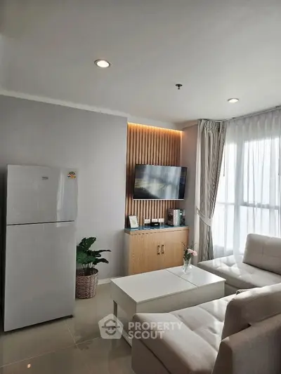 Modern living room with sleek design, featuring a cozy sofa, flat-screen TV, and a stylish refrigerator.