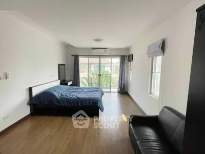 Spacious bedroom with modern decor and large windows offering natural light and garden view.