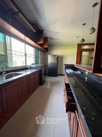 Spacious kitchen with modern appliances and ample natural light, featuring sleek countertops and wooden cabinetry.