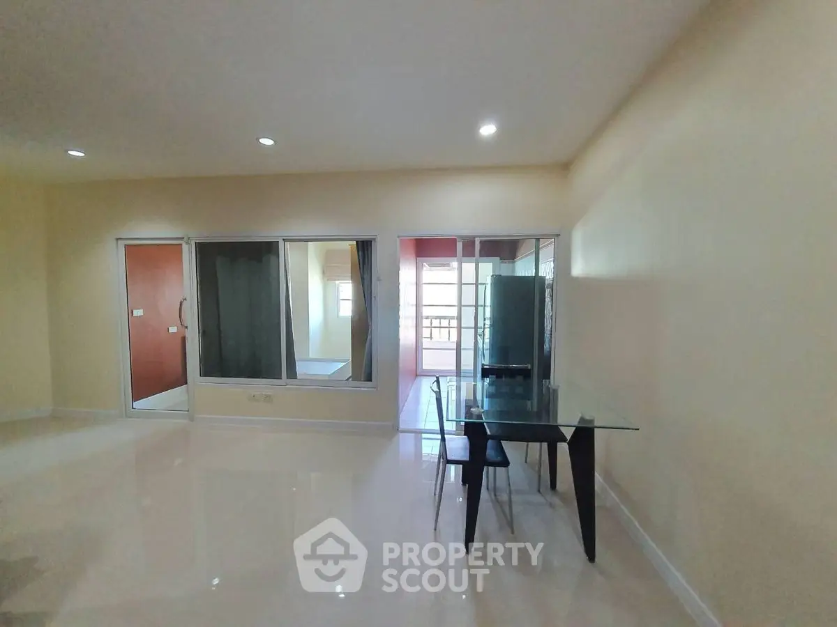 Spacious modern living room with glass table and sliding doors to balcony