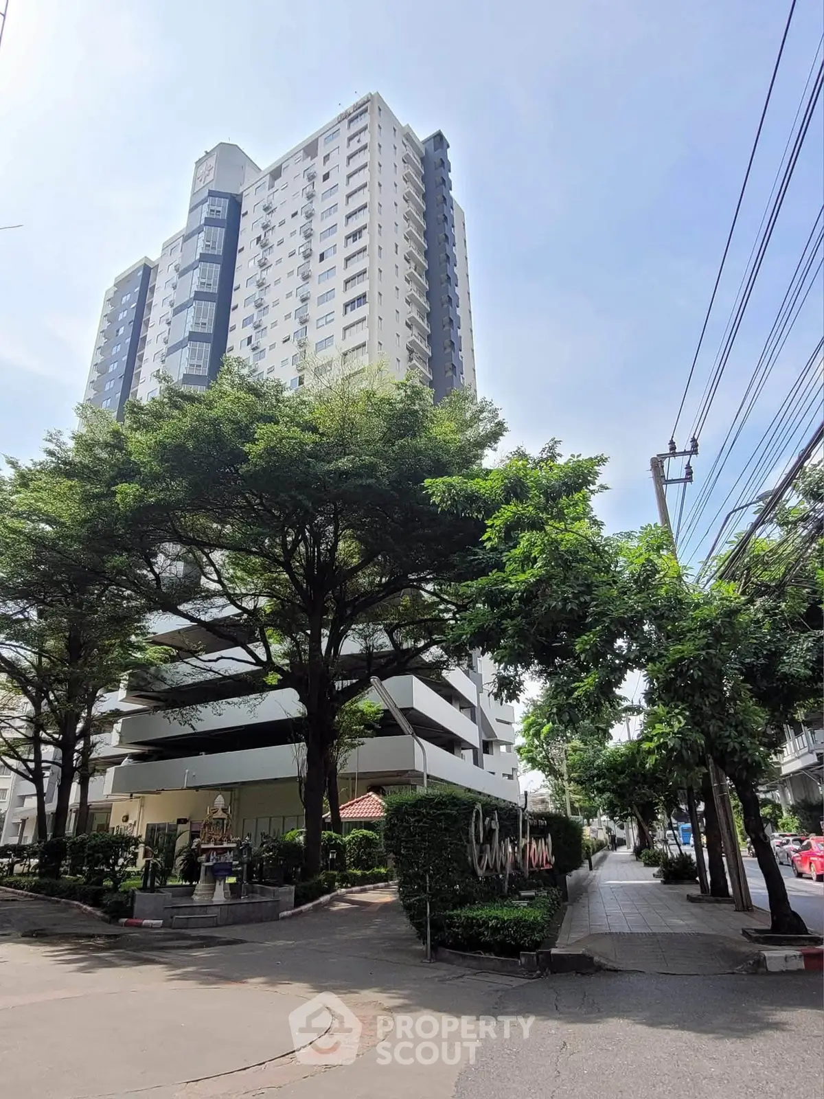 Modern high-rise building with lush greenery and clear blue sky, ideal urban living.