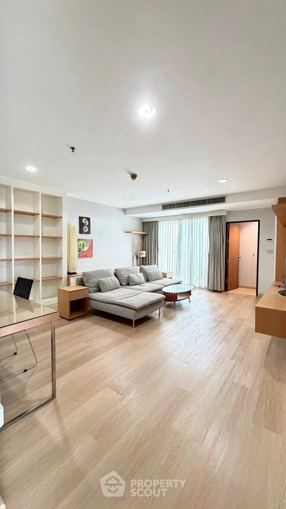 Spacious modern living room with wooden flooring and large windows for natural light.