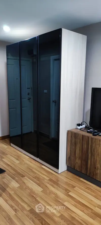 Modern living room with sleek black wardrobe and wooden TV stand
