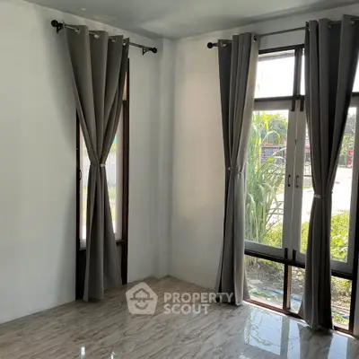 Bright corner room with large windows and elegant curtains, perfect for natural light lovers.