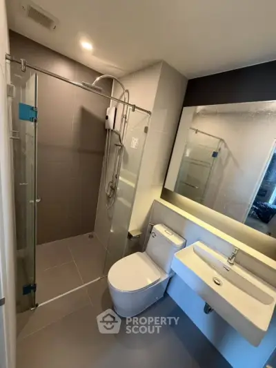 Modern bathroom with glass shower and sleek fixtures in contemporary apartment.