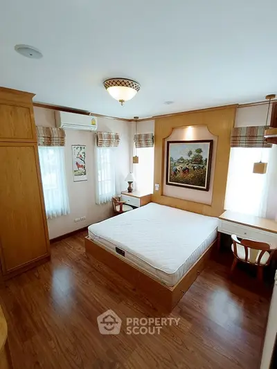Cozy bedroom with wooden furniture and natural light, featuring a stylish bed and elegant decor.